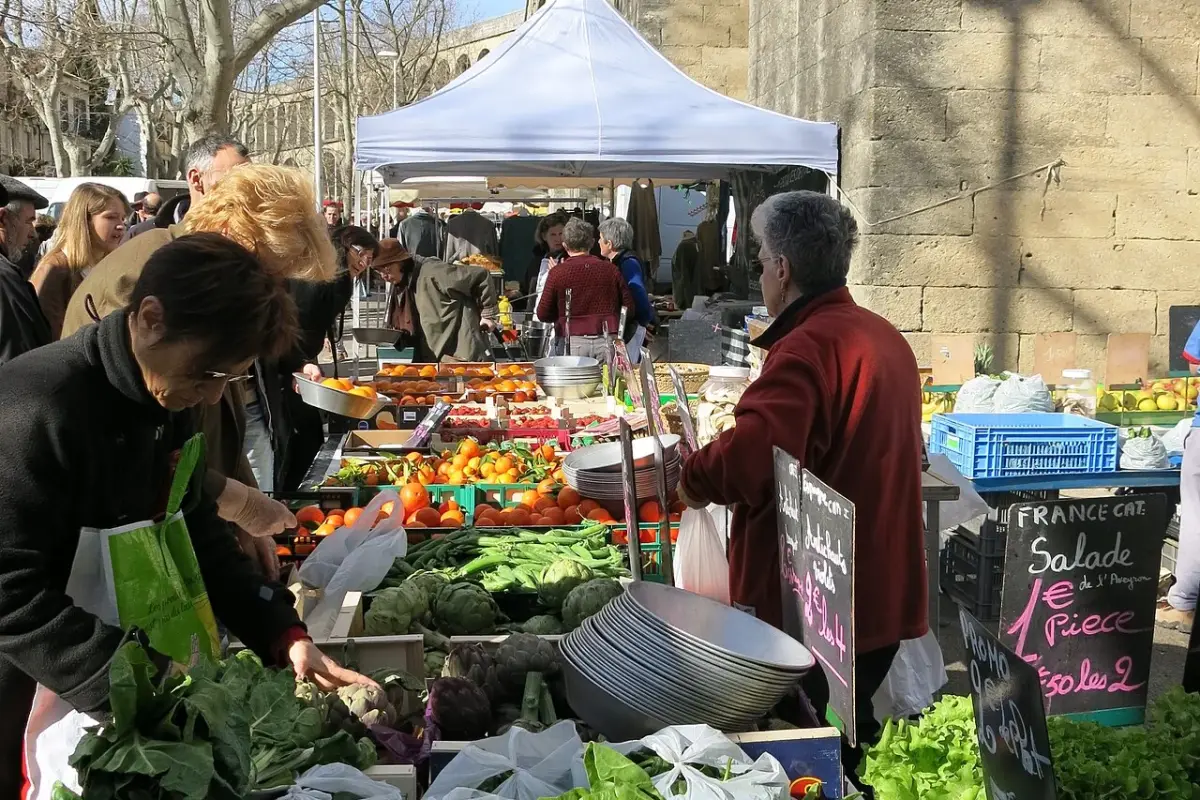 Étals de légumes et de fruits au pied des arches de l’aqueduc Saint-Clément, un jour de marché aux Arceaux, à Montpellier