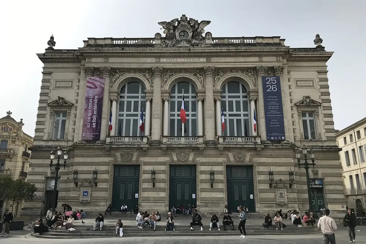 La façade de l’Opéra Comédie, place de la Comédie à Montpellier, avec des passants assis sur les marches