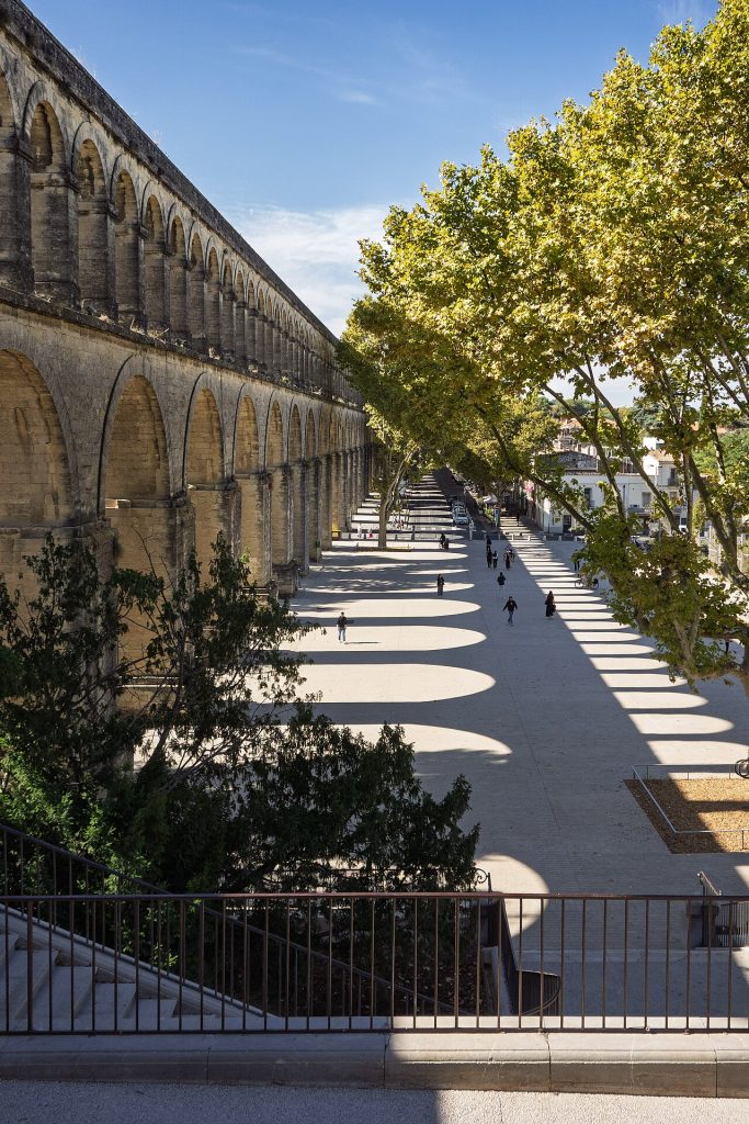 L’aqueduc Saint-Clément et ses arches aux Arceaux, bordant une vaste esplanade ombragée d’arbres, vue en surplomb