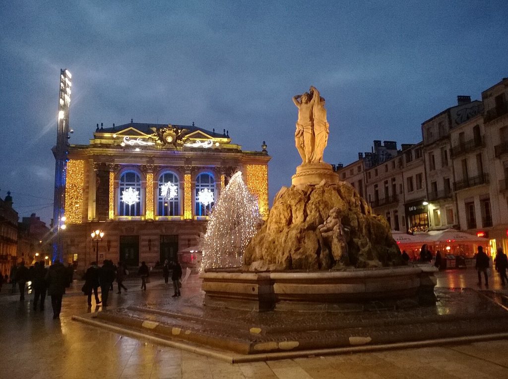 L’Opéra Comédie illuminé pour les fêtes et un sapin lumineux derrière la fontaine des Trois Grâces, à la tombée de la nuit