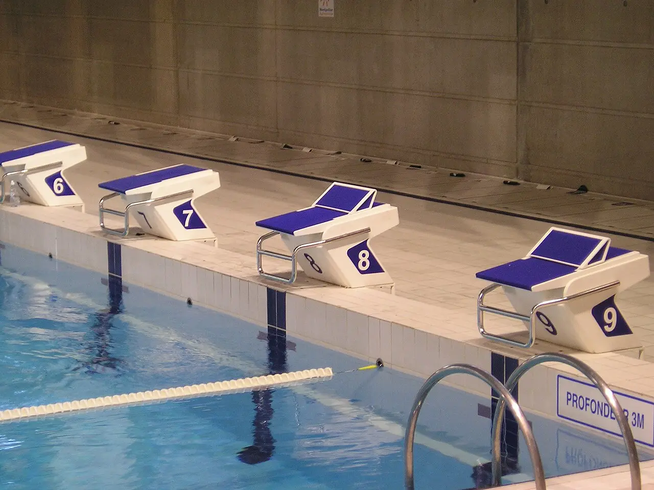 Plots de départ numérotés au bord du bassin de la piscine olympique d’Antigone