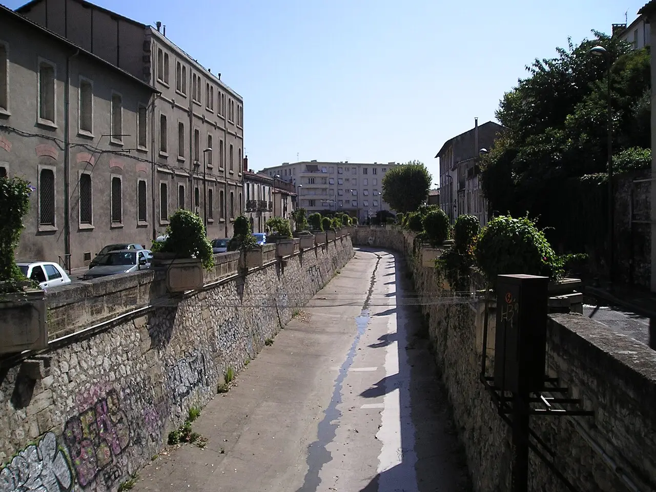 Le lit bétonné du Verdanson entre deux murs de pierre couverts de graffitis, bordé d’immeubles